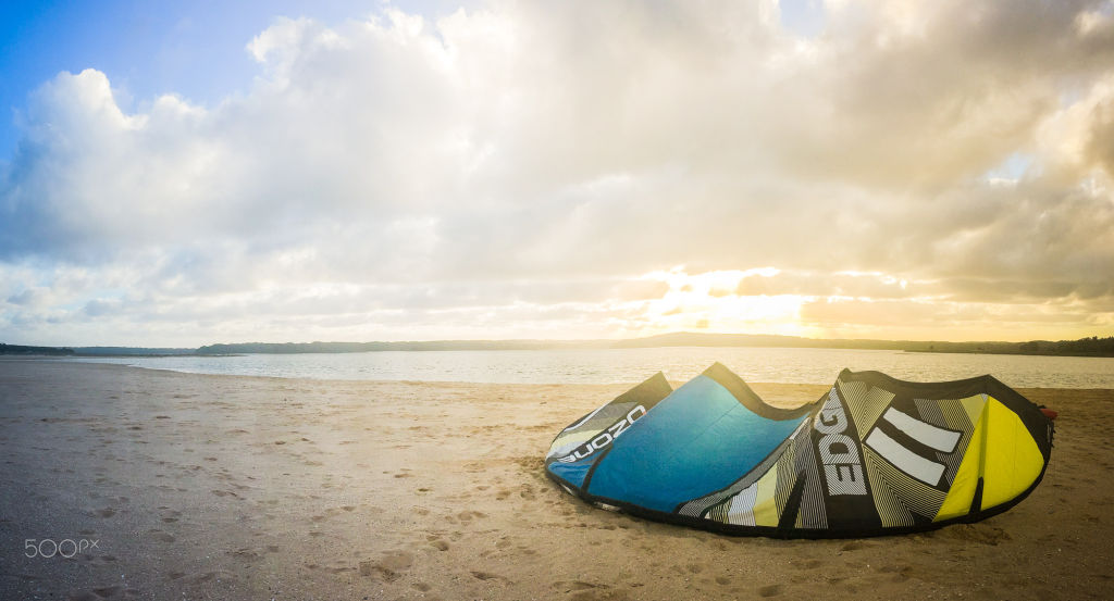 A kite lying on the sand at sunset