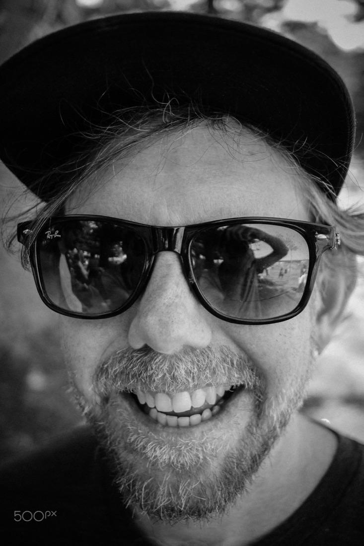 Black and white portrait of a smiling man in sunglasses and a cap