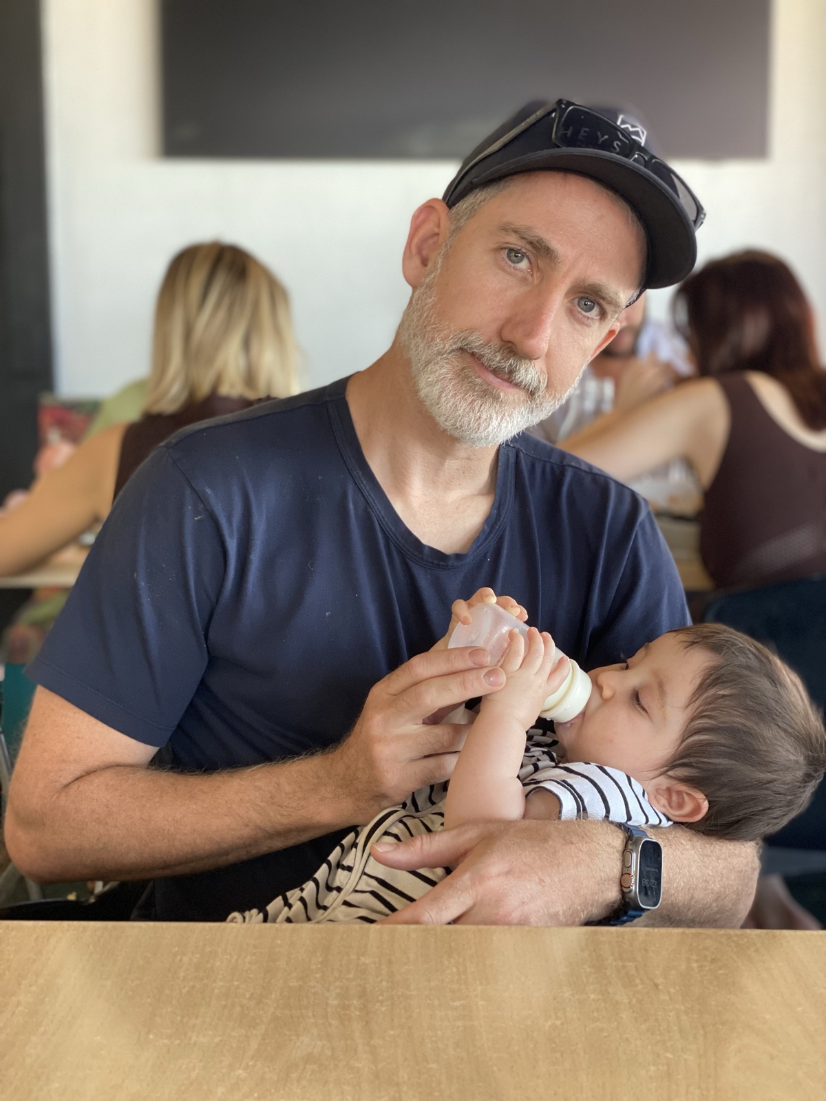 Pierre bottle-feeding the baby at a cafe