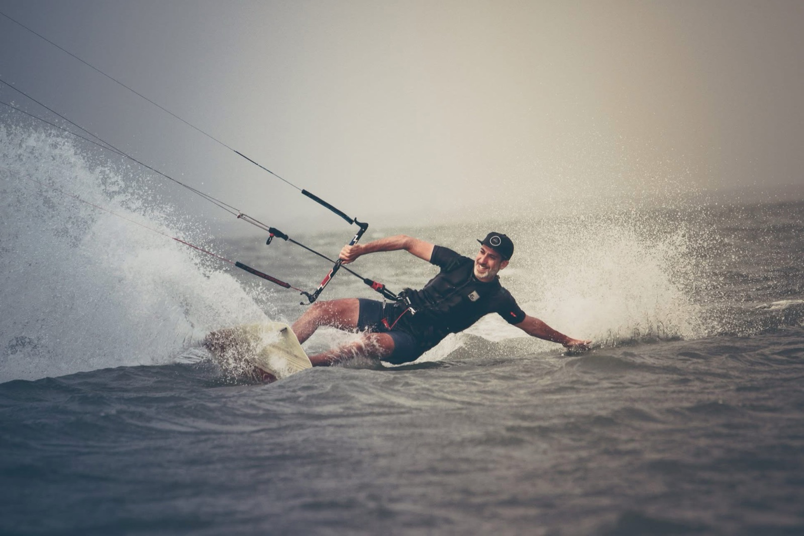 Pierre kitesurfing, leaning hard into a turn through the spray